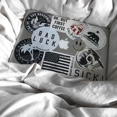 an apple laptop sitting on top of a bed covered in white sheets and stickers