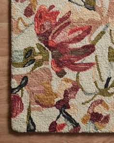 an area rug with flowers and leaves on the floor in front of a wooden surface