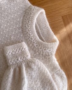 a white knitted sweater sitting on top of a wooden floor