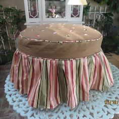 a large round ottoman covered in pink, green and white striped fabric on a table