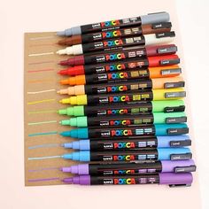 many different colored markers are lined up on a piece of paper