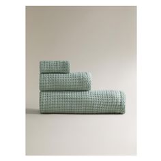 three towels folded on top of each other in different colors and patterns, one is green