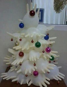 a white christmas tree with ornaments on it's branches and hands sticking out of the top