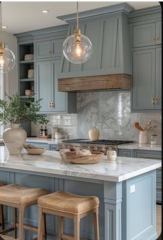 a kitchen with blue cabinets and white marble counter tops, two stools in front of the island