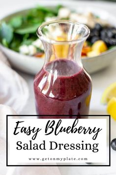 blueberry salad dressing in a glass bottle with lemons and spinach on the side