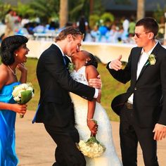 a bride and groom hug each other as they walk down the street with their friends