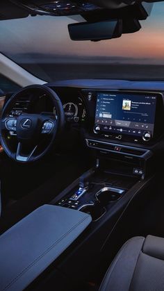 the interior of a car with dashboard, steering wheel and touch screen showing at dusk