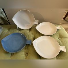 three white and blue dishes sitting on top of a green cushion