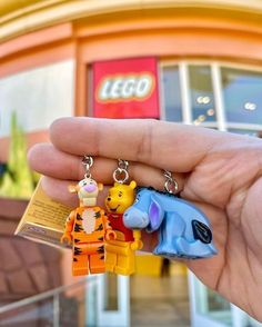 someone is holding two key chains in front of a lego store with winnie the pooh and tigger