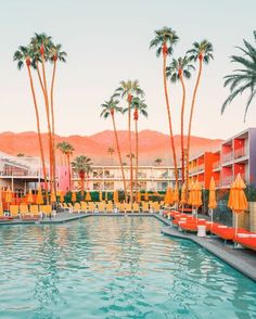 an outdoor swimming pool with yellow chairs and palm trees in front of the resort buildings