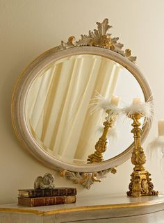 a mirror sitting on top of a dresser next to a vase and candlesticks