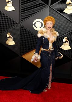 a woman in a black dress and fur stole on the red carpet at an awards event