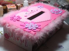 a pink and white box with flowers on the inside sitting on a table next to other items