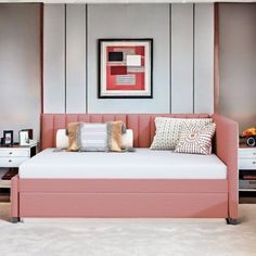 a pink daybed in the corner of a room with two nightstands and a painting on the wall