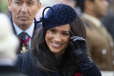 the woman is wearing a blue hat and holding her hand up to her face as she smiles