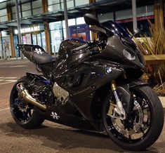 a black motorcycle parked in front of a tall building at night with its lights on