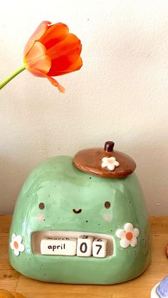 an alarm clock sitting on top of a wooden table next to a tulip flower