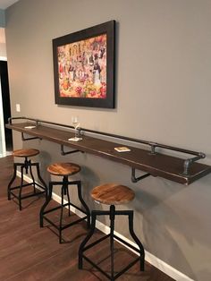 three bar stools are lined up against the wall in front of a framed painting