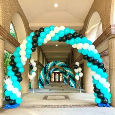 an archway decorated with black, white and blue balloons in the middle of a hallway