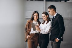 three business people looking at something on a clipboard in front of them are standing next to each other