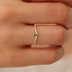 a woman's hand with a diamond and emerald ring on her finger, showing the band