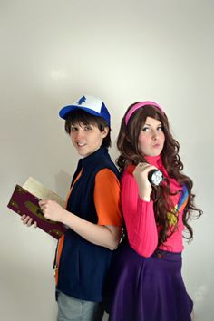 two people standing next to each other in front of a white wall wearing hats and holding books