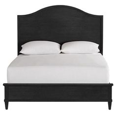 a bed with white pillows and black headboard