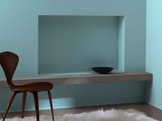 a wooden chair sitting on top of a white rug in front of a blue wall