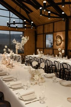 the tables are set up with white flowers and place settings for an elegant wedding reception