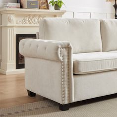 a white couch sitting on top of a hard wood floor next to a fire place