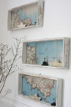 three maps mounted on the wall above a vase with flowers in it and one is upside down