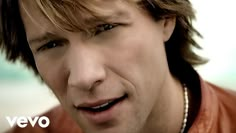 a close up of a person wearing a leather jacket and smiling at the camera with his mouth open