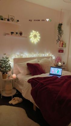 a laptop computer sitting on top of a bed in a room with white walls and lights