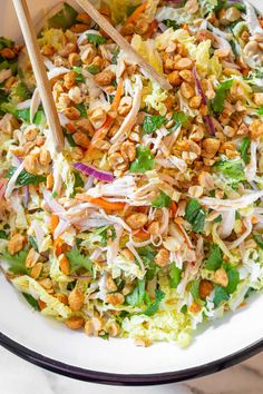 a white bowl filled with salad and chopsticks