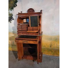 an old wooden desk with drawers and a mirror on it's top, in front of a painted wall