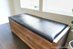 a wooden bench sitting in front of a window next to a potted plant on top of a hard wood floor