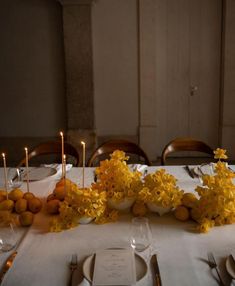 the table is set with yellow flowers and candles