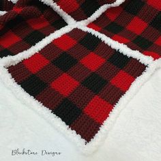 a red and black checkered blanket laying on top of a white bed coverlet