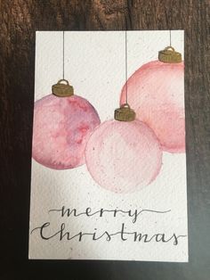 a christmas card with pink ornaments hanging from strings