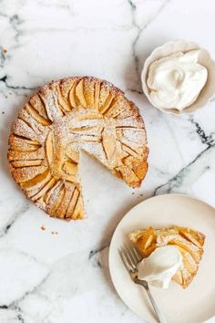 a piece of pie sitting on top of a white plate next to a bowl of whipped cream