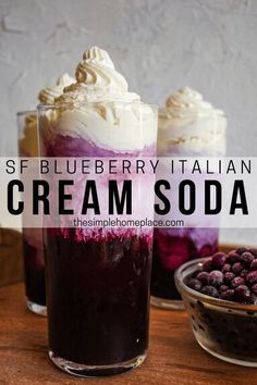 two glasses filled with ice cream and berries on top of a wooden table next to a bowl