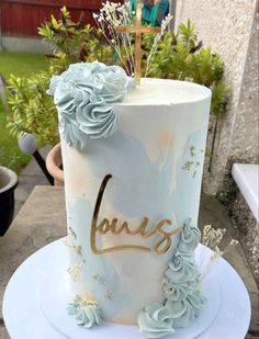 a white cake with blue flowers and the word louis on it is sitting on a plate