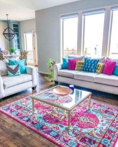 a living room with couches, chairs and rugs in front of large windows