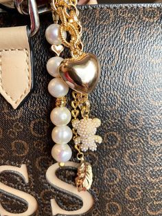 a close up of a handbag with pearls and charms attached to it's handle