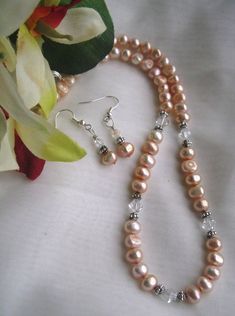 Beautiful peach-colored, real freshwater pearls. The different shapes and unique imperfections makes this a unique one-of-a-kind piece. Metal and real Swarovski crystal accents complete this necklace, with the same materials used in the matching earrings. Elegant Orange Pearl Necklace Gift, Elegant Peach Round Beads Necklaces, Elegant Peach Necklaces With Round Beads, Elegant Beaded Coral Pearl Necklace, Elegant Orange Pearl Drop Jewelry, Elegant Coral Jewelry With Pearl Drop, Peach Pearl Jewelry For Gifts, Peach Pearl Jewelry As Gift, Peach Pearl Jewelry For Gift