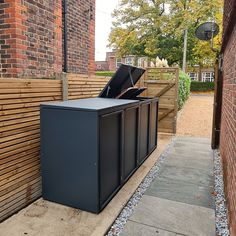 a black trash can sitting next to a brick building