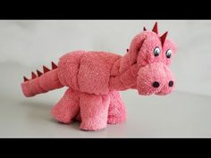 a pink dragon stuffed animal sitting on top of a table