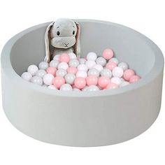 a stuffed animal sitting in a bowl filled with pink, white and grey balls on top of it