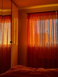 a bedroom with orange curtains and a bed