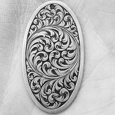 an intricately designed oval pendant hangs on a white fabric background in black and white